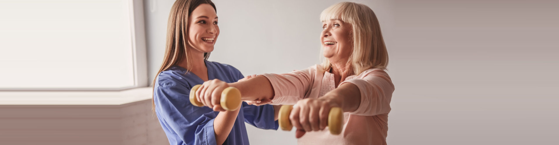 elder woman exercising with caregiver supporting her