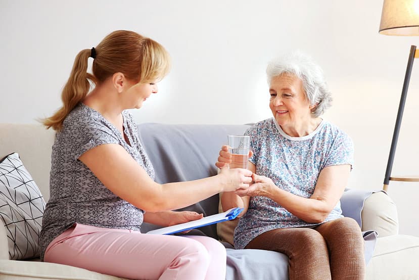 caregiver giving elder woman a glass of water